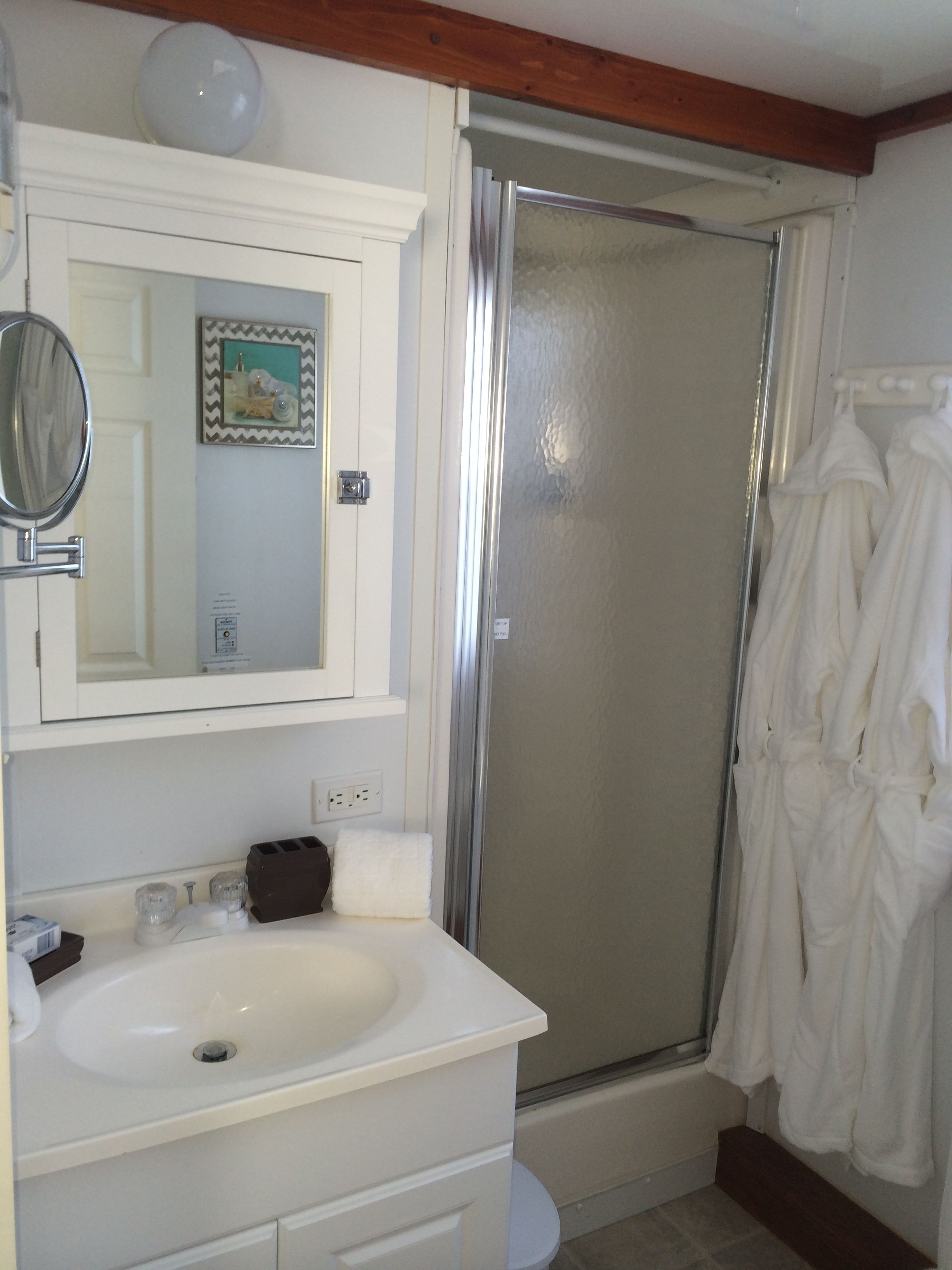 A bathroom with a white sink, mirror, and a shower enclosure.