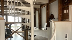 A spiral staircase with white railings and black steps, leading to a wooden deck area with outdoor seating. - Mangrove Marina and Resort Aqualodge Houseboats (Tavernier)