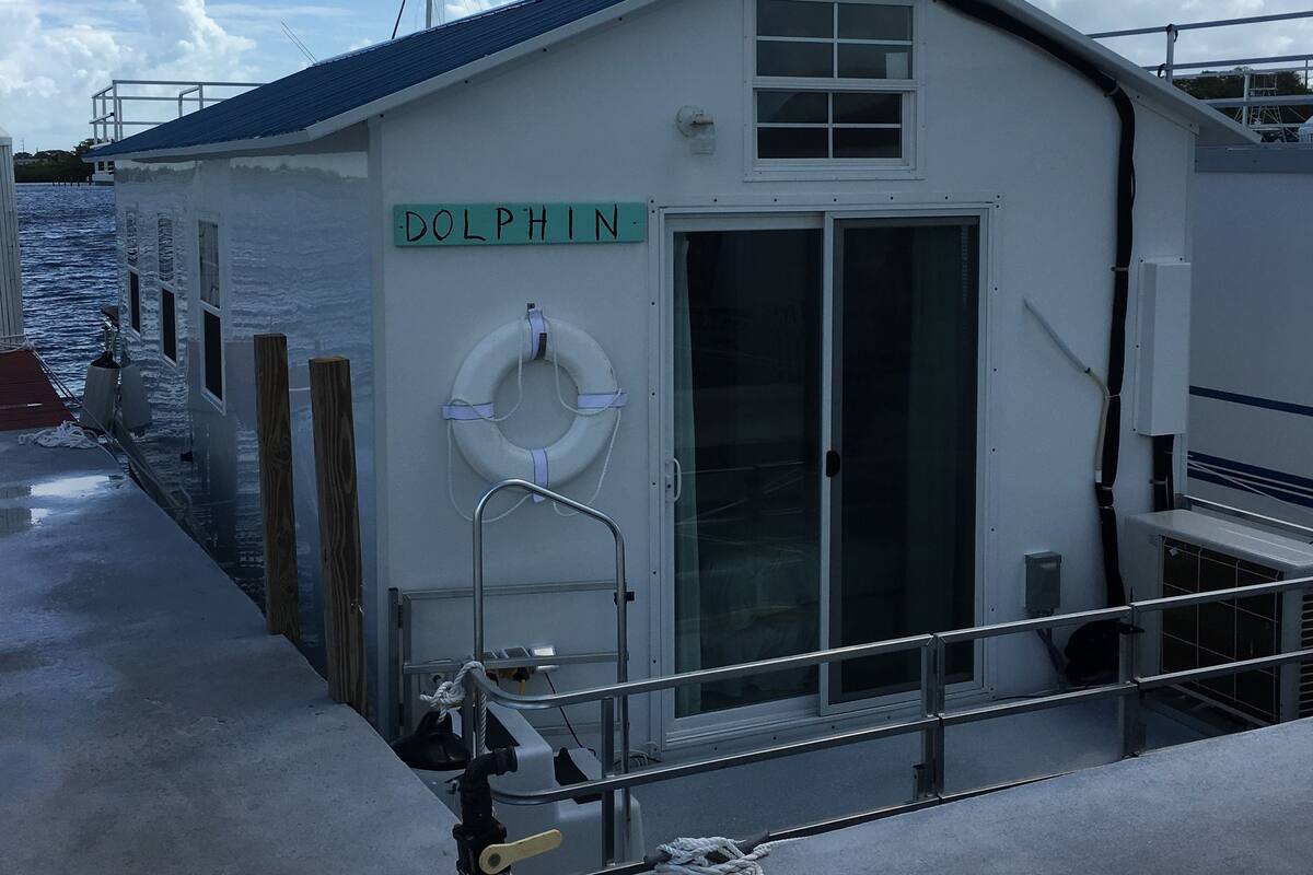 En lille bygning med teksten 'DOLPHIN', en redningskrans, en dør og et vindue.