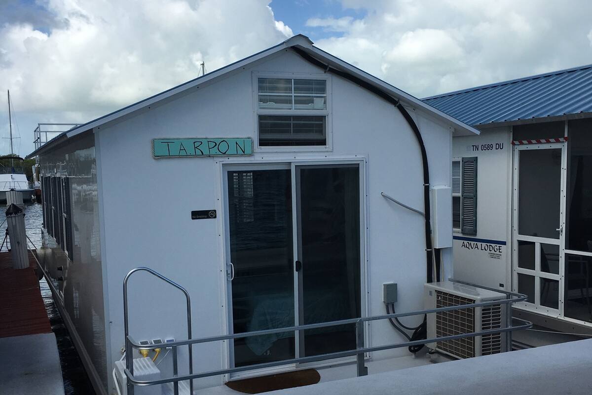 En hvid bygning med skilt, der viser "TAPON" og "AQUA LODGE".