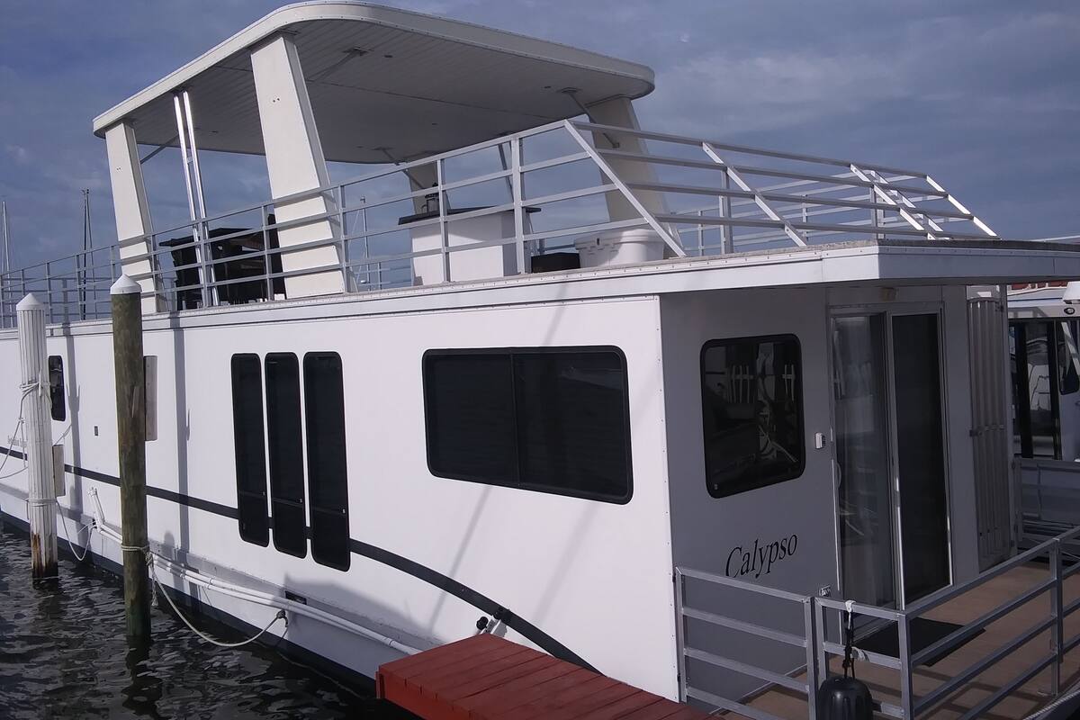 En hvid båd med et overdækket dæk, vinduer og navnet 'Calypso' på siden.