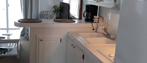 A kitchen with white cabinets, a built-in oven, and a coffee maker.