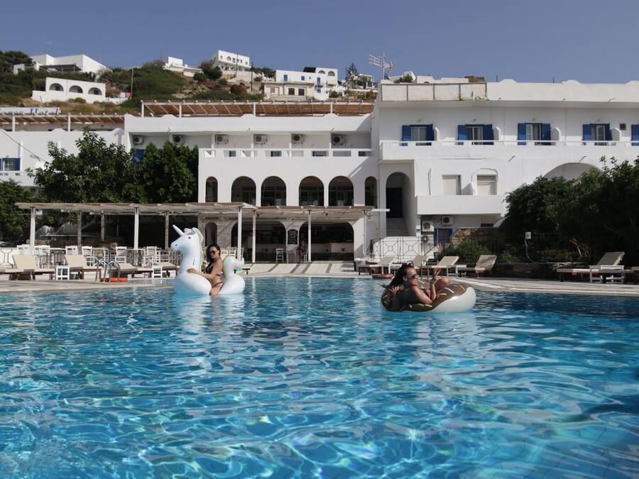 Una piscina al aire libre, sombrillas, sillones reclinables de piscina