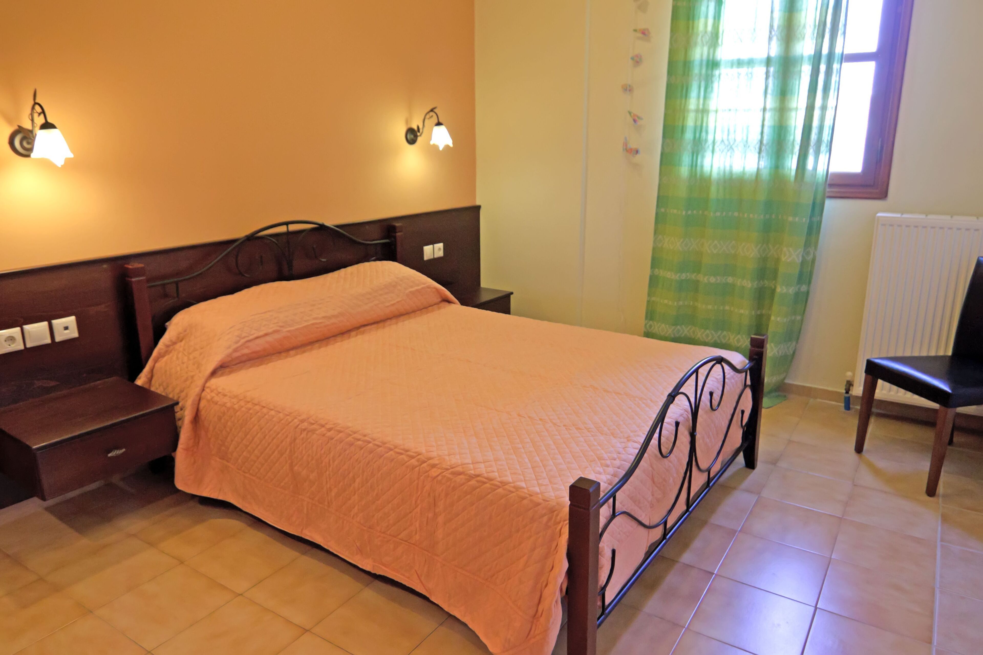 A bedroom with a bed, nightstands, a chair, and wall-mounted lights.