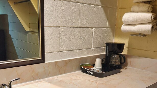 A bathroom with a marble sink, a coffee maker, and towels on a rack. - Budget Inn (Bartlesville)