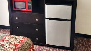 A compact kitchenette with a microwave, a small refrigerator, and a television on a cabinet. - Budget Inn (Bartlesville)
