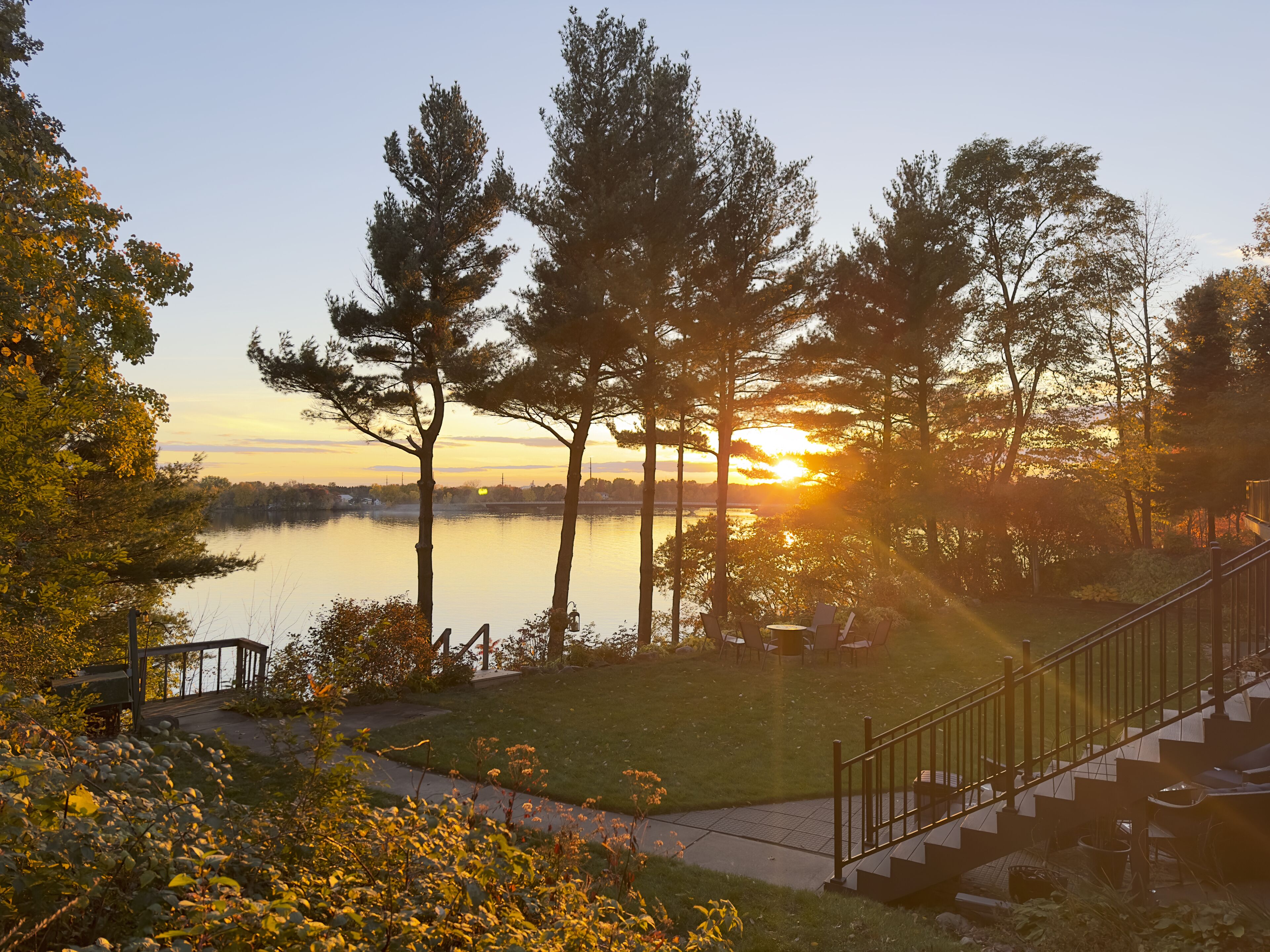 Une vue sur le lac, avec une terrasse en bois et des chaises donnant sur l’eau.