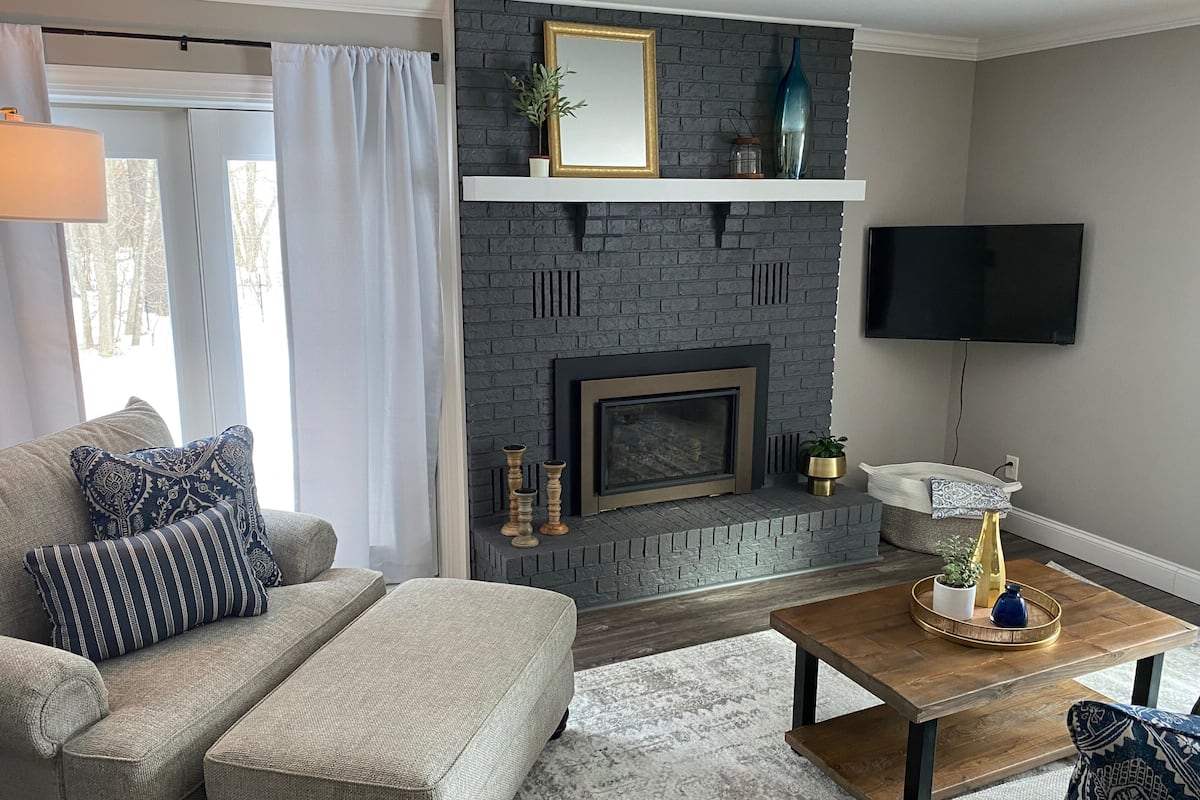 A living room with a fireplace, a sofa, a coffee table, and a TV mounted on the wall.