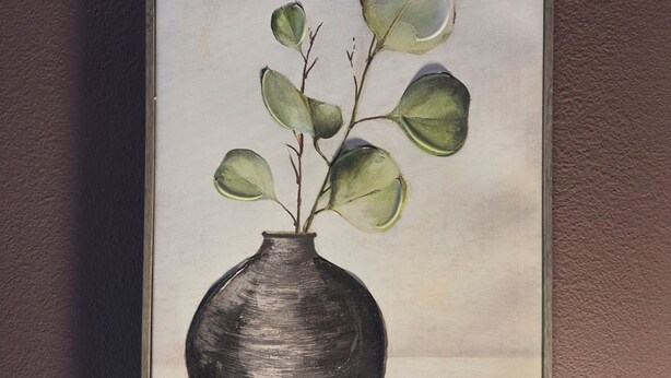 A framed painting of a vase with green leaves. - Inn On Lake Wissota (Chippewa Falls)