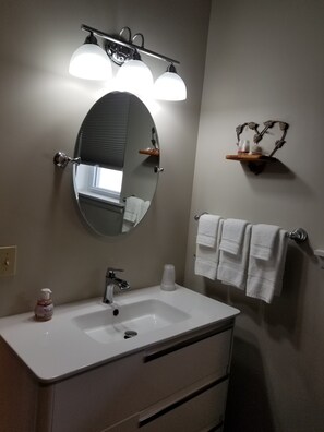 A bathroom with a white sink, a mirror, and a towel rack.