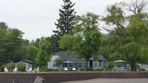 A lakeside property with a house, outdoor seating, and a dock.