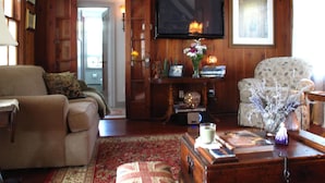 A cozy living room with a sofa, armchair, and a television mounted on the wall.