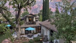 Una casa con patio, comedor y vistas a una cadena montañosa.