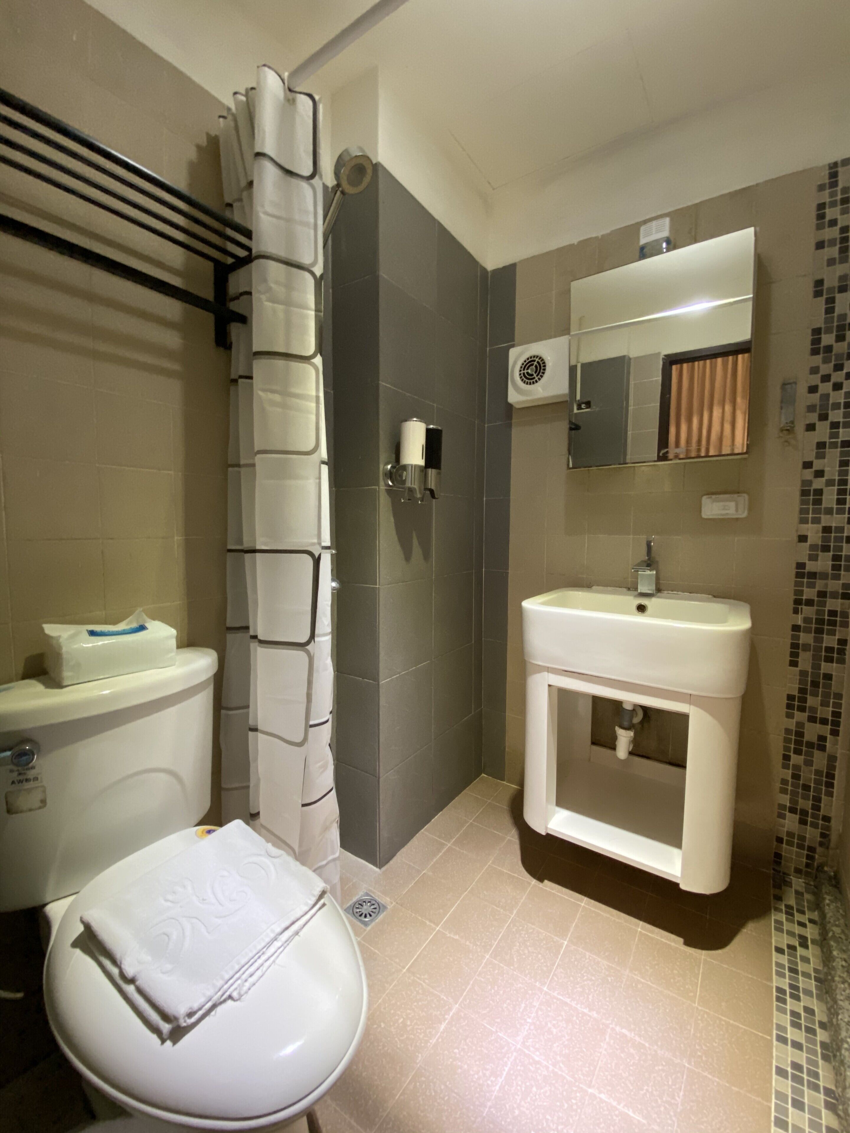 Un baño con inodoro, lavamanos, ducha y espejo.