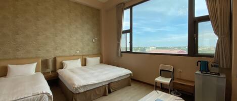 Habitación de hotel con dos camas, una mesita, una silla, una ventana con vistas y un candelabro.