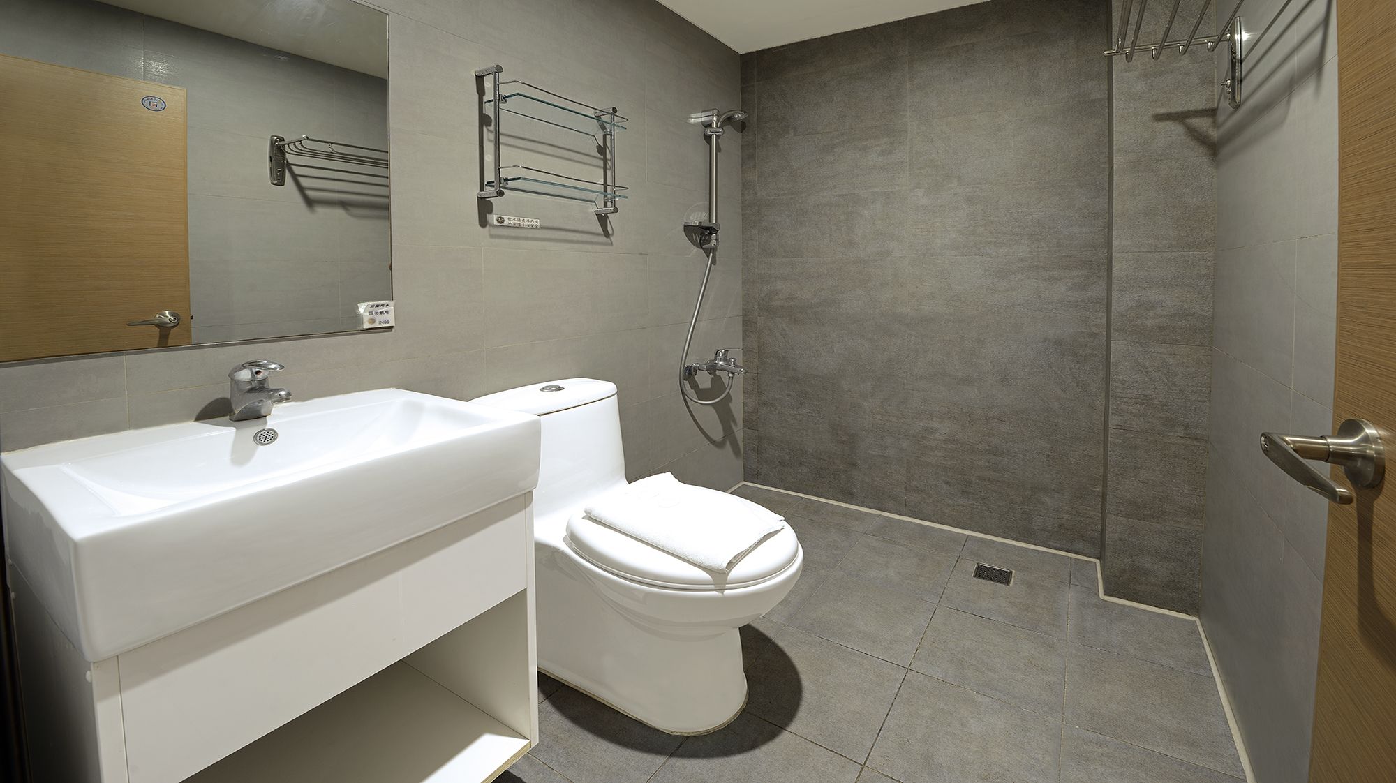 A modern bathroom with a white sink, toilet, and shower.