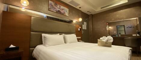 A hotel room with a large bed, a headboard, a bedside table, a mirror, and a wall-mounted artwork.