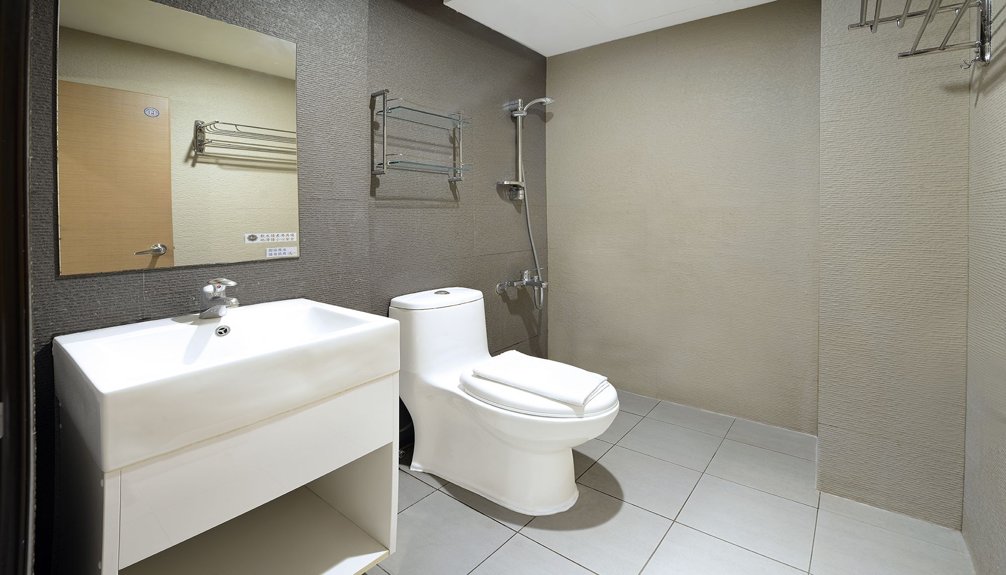 A modern bathroom with a white sink, toilet, and shower.