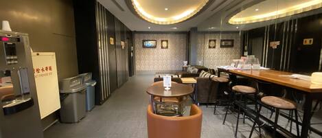 A modern hotel lobby with a bar area, seating, and a coffee machine.