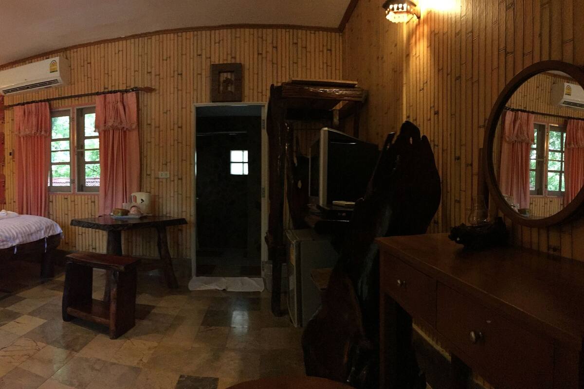 Une pièce avec deux lits en bois, une petite table, un miroir et une porte donnant sur une autre pièce.