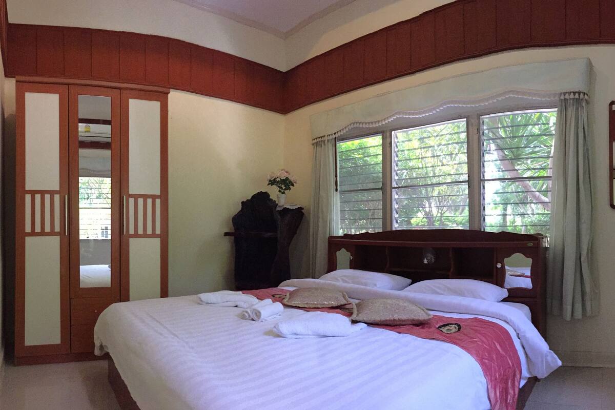 Une chambre à coucher avec un grand lit, une armoire et une fenêtre avec des rideaux.