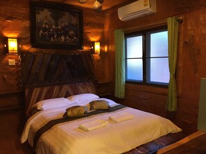 Ein Zimmer mit Holzboden, einem Bett, einem Bild an der Wand und einer Klimaanlage.