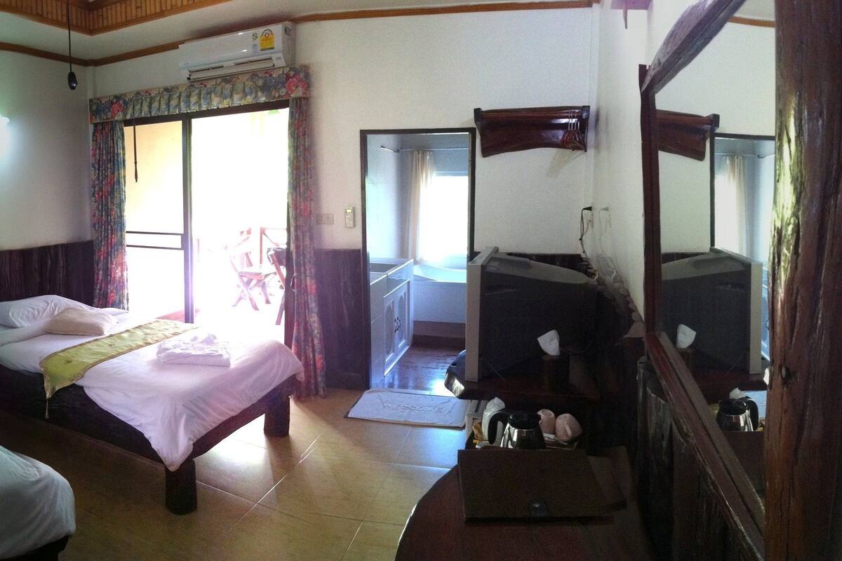 Une chambre d’hôtel avec deux lits, un grand miroir, un bureau et une fenêtre avec des rideaux.