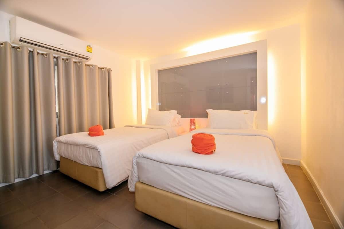 Habitación de hotel con dos camas, un ventanal grande y un equipo de aire acondicionado.