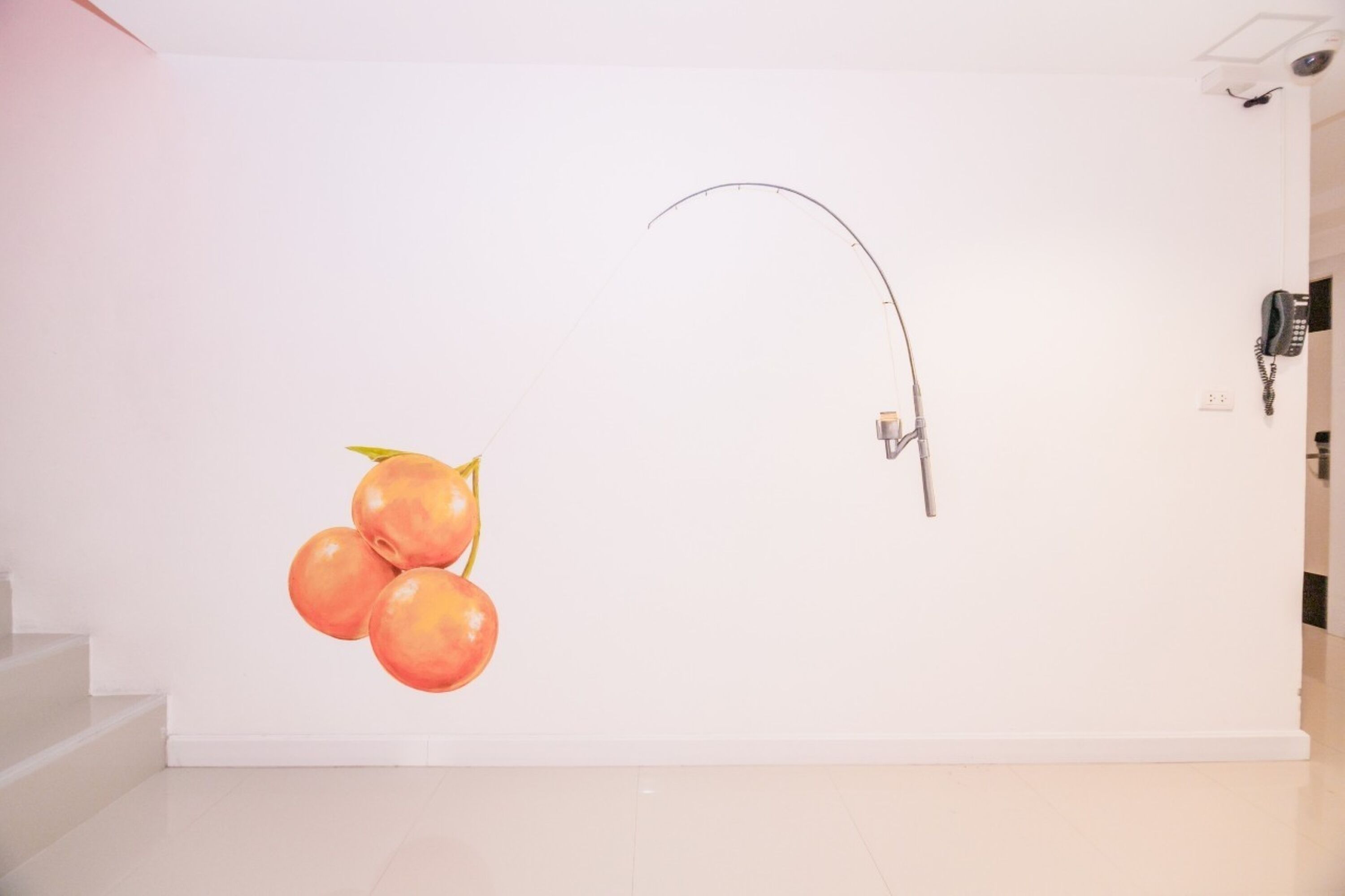Pared blanca con una pintura de melocotones y una tubería curvada.