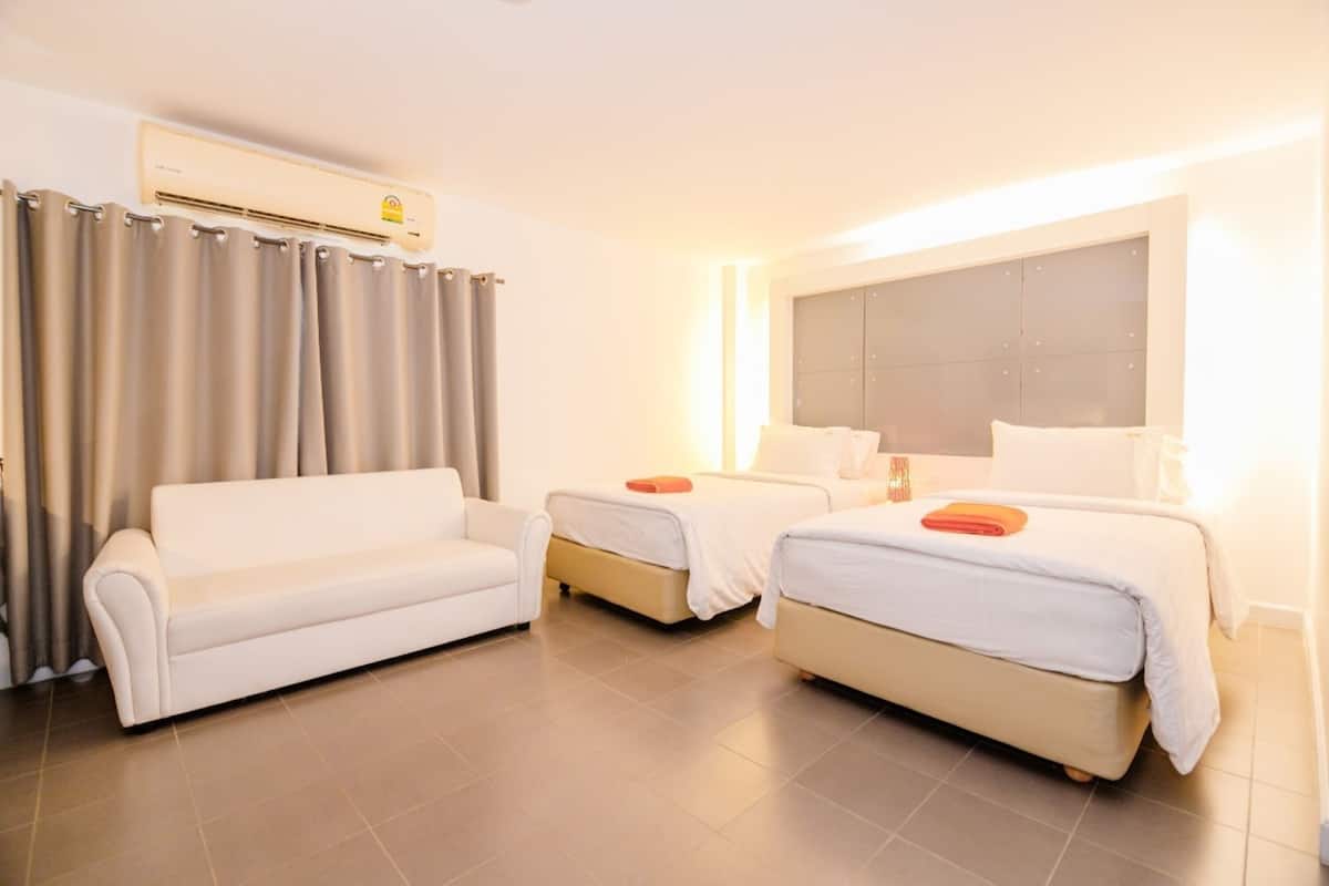 Una habitación de hotel con dos camas, un sofá y un equipo de aire acondicionado.