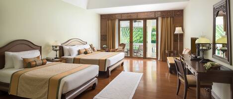 A hotel room with two beds, a desk, and a balcony with curtains.