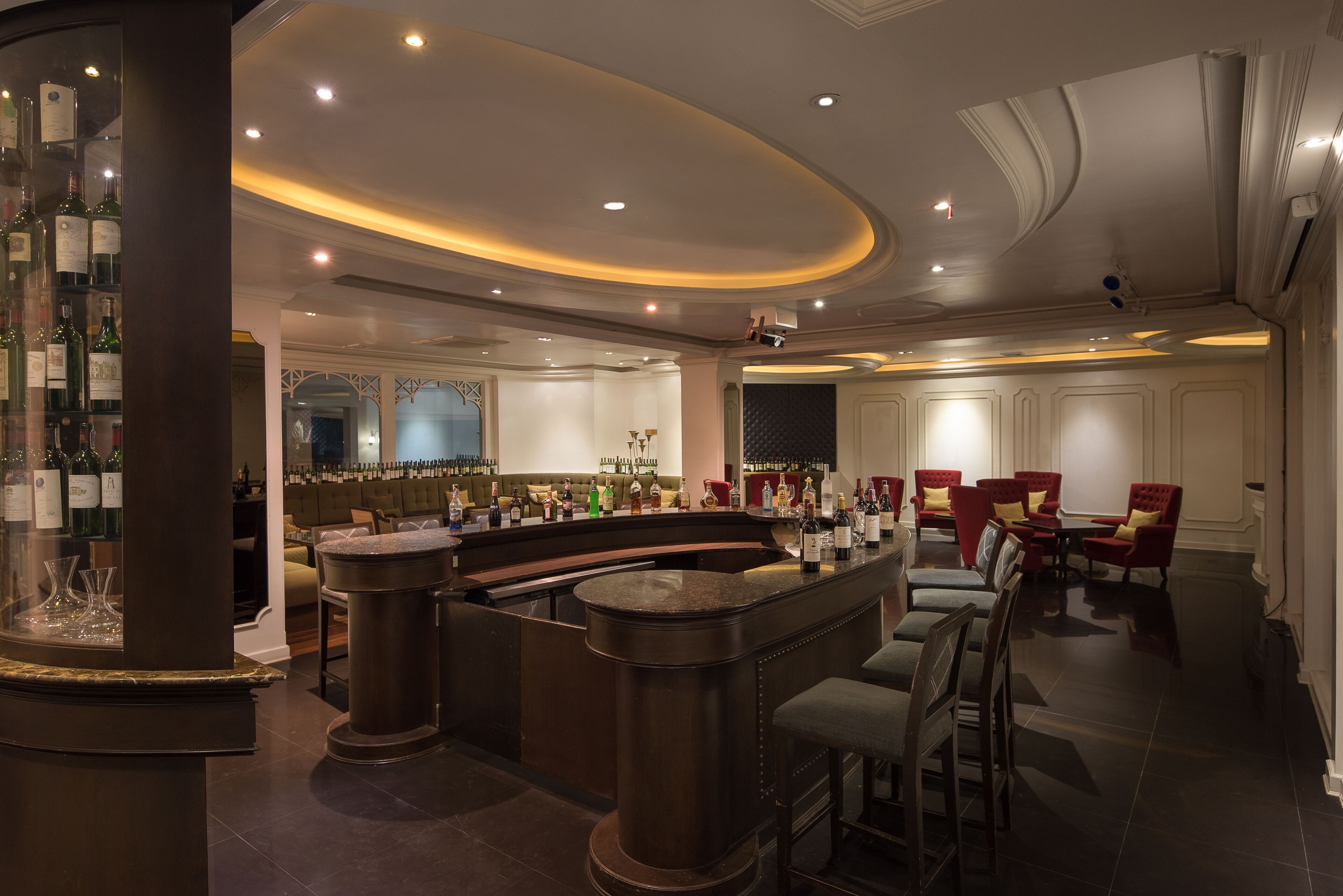 A bar area with a curved counter, seating, and a display of bottles.