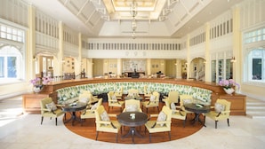 A spacious lobby with a central seating area, a reception desk, and a high ceiling with intricate designs.
