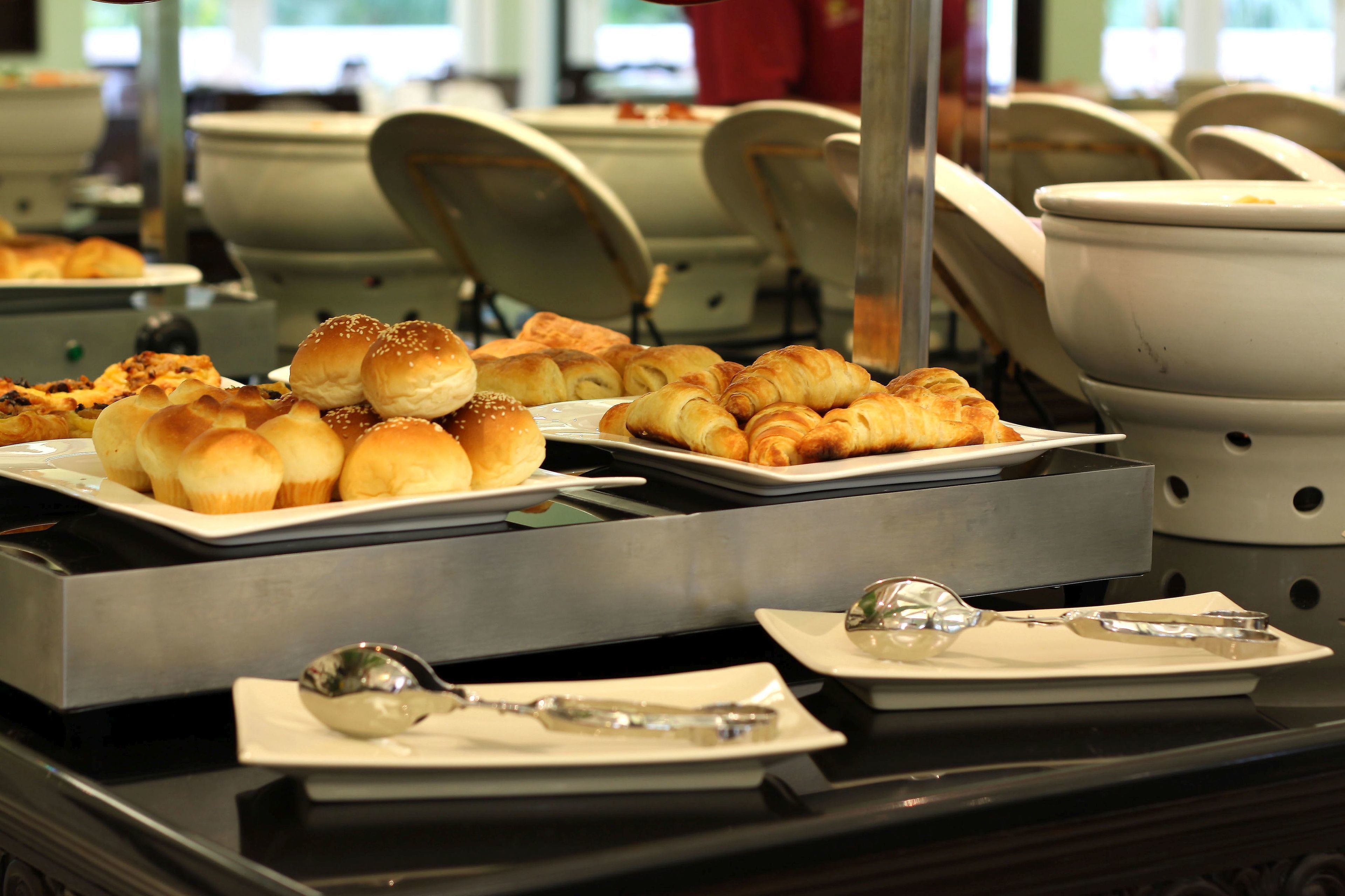 A buffet setup with various baked goods and utensils.