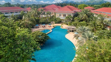 Relax by the resort's inviting pool surrounded by lush greenery and palm trees.