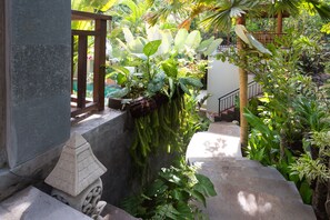 A stone staircase leading up to a wooden deck surrounded by lush tropical plants. - Puri Payogan Villa Ubud (Ubud)