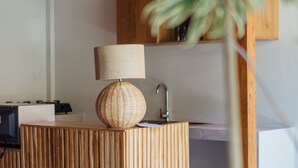 A modern kitchen with a wooden island, a woven lamp, and a sink. - Puri Payogan Villa Ubud (Ubud)