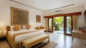 A modern hotel room with a large bed, a wooden bench, a desk, and a view of the outdoors. - Puri Payogan Villa Ubud (Ubud)
