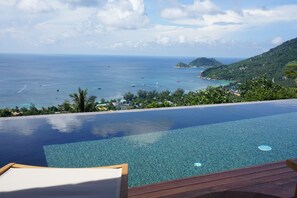 An infinity pool with a clear view of the ocean and a hilly landscape. - Naroua Villas (Koh Tao)