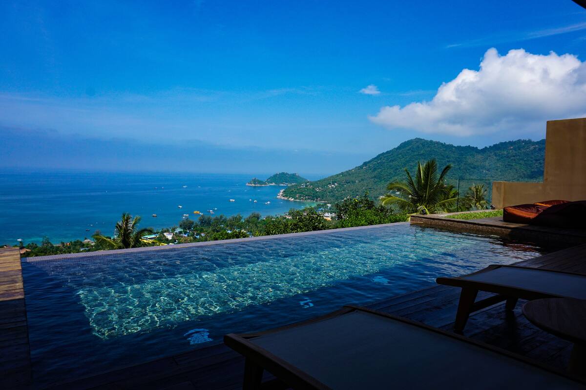Una piscina infinita con vistas despejadas al océano y un paisaje montañoso.