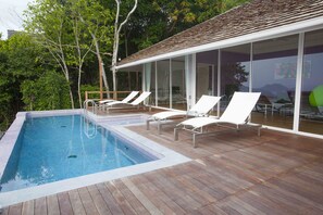 A swimming pool with lounge chairs and a covered patio area. - Naroua Villas (Koh Tao)