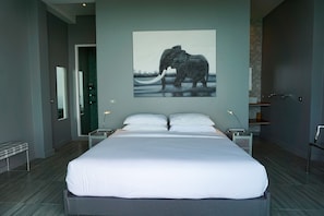 A modern bedroom with a large bed, a painting of an elephant, and a minimalist design. - Naroua Villas (Koh Tao)