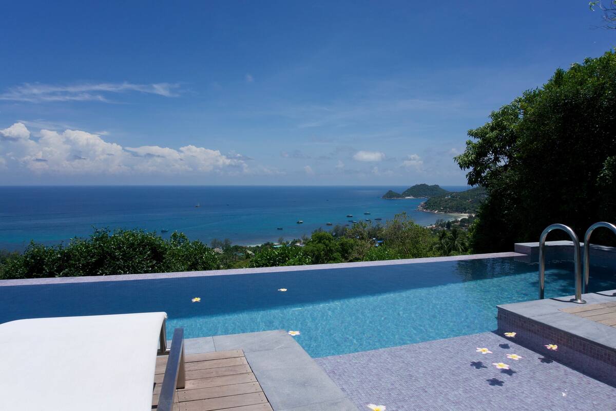 Una piscina infinita con vistas al océano y una isla distante.