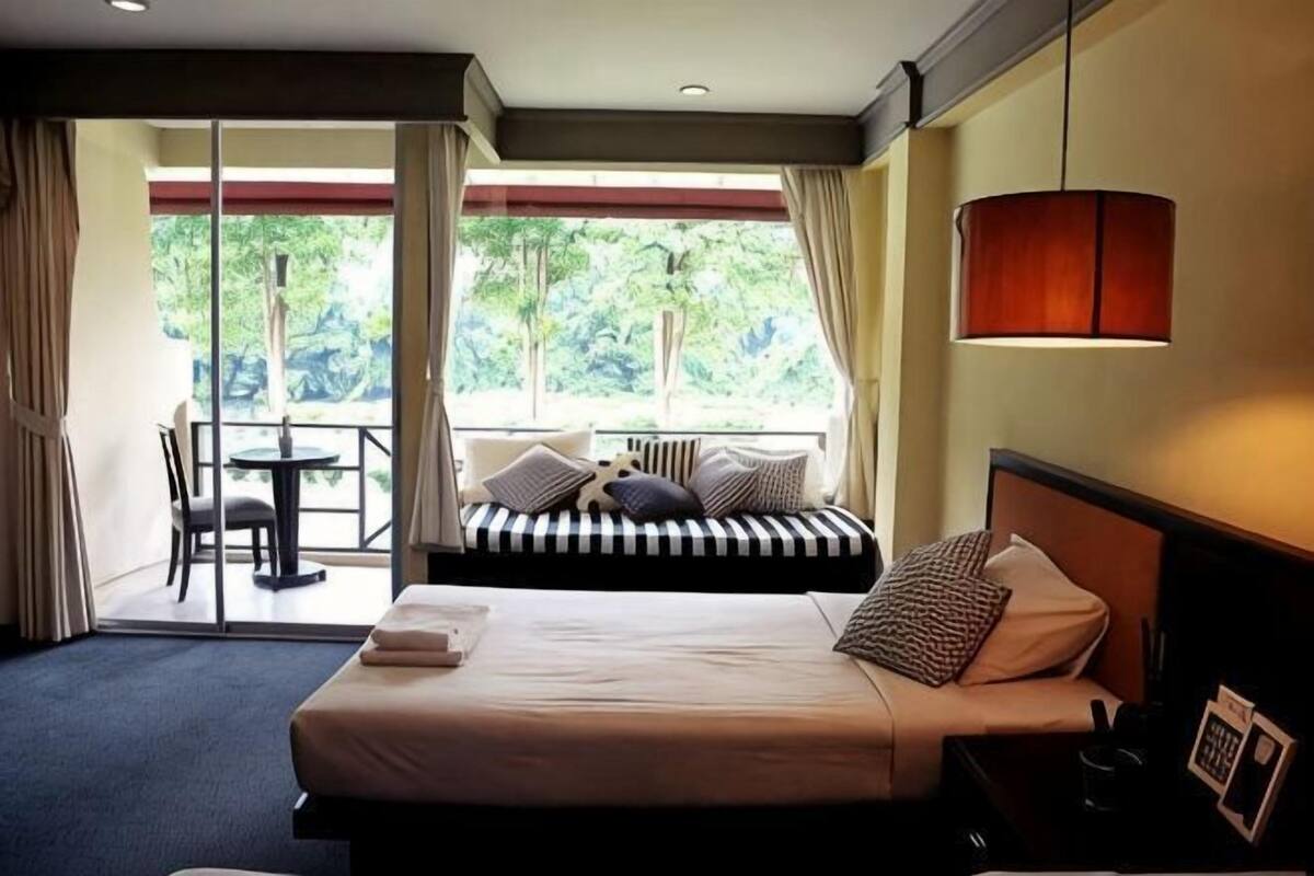 Une chambre d’hôtel avec un lit, une table de chevet, une lampe et une vue sur l’extérieur.