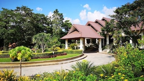 A hotel with a covered outdoor area, surrounded by well-maintained gardens and trees. - Aekpailin River Kwai Resort Kanchanaburi (Kanchanaburi)