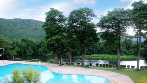 A swimming pool surrounded by trees and a lake. - Aekpailin River Kwai Resort Kanchanaburi (Kanchanaburi)
