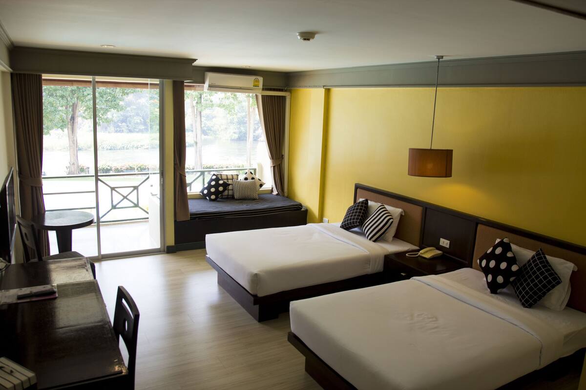Une chambre d’hôtel avec deux lits, un bureau et une vue sur un balcon.
