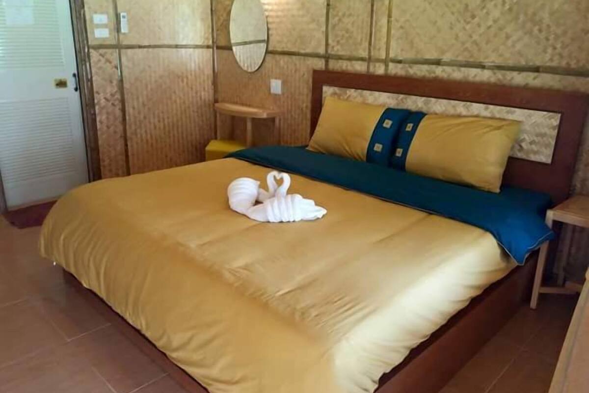 Ein Hotelzimmer mit einem großen Bett, einem Holzkopfschild und einem Nachttisch.