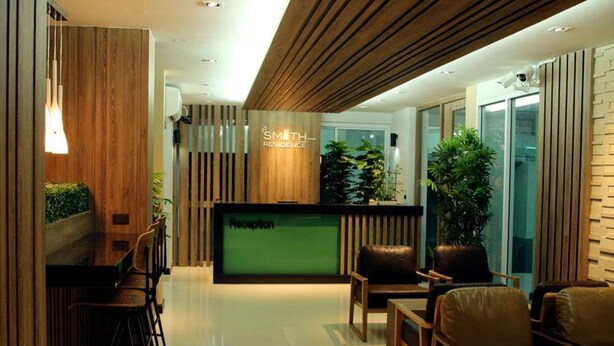 Una moderna zona de recepción con mostrador, asientos y plantas en macetas.
