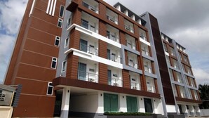 Un edificio residencial de varios pisos con diseño moderno, con balcones en cada planta y zona de estacionamiento techada.